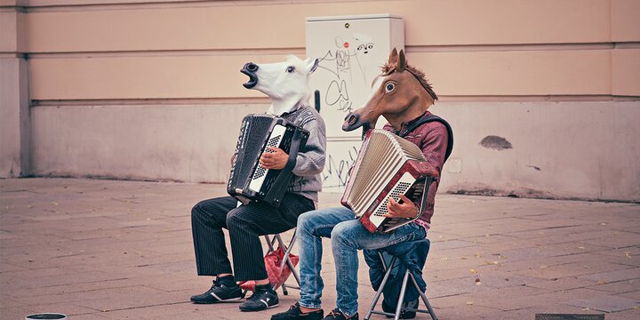 Two people in horse head masks playing accordians