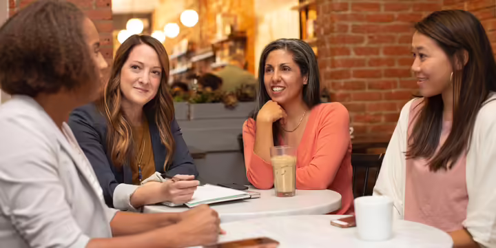 A group of women sitting around at a table talking.