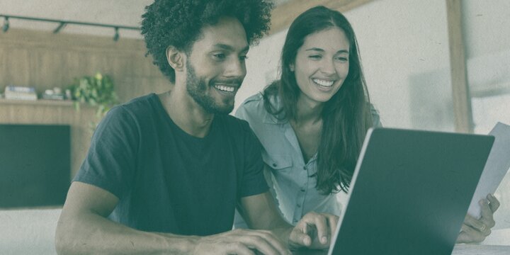man and woman smiling and looking at a laptop screen