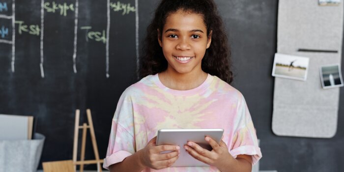 girl holds ipad to read the newsletter