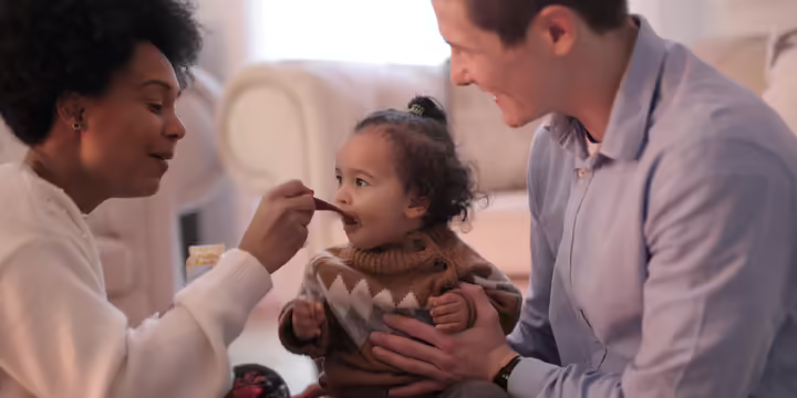 A woman and a man feeding their baby.