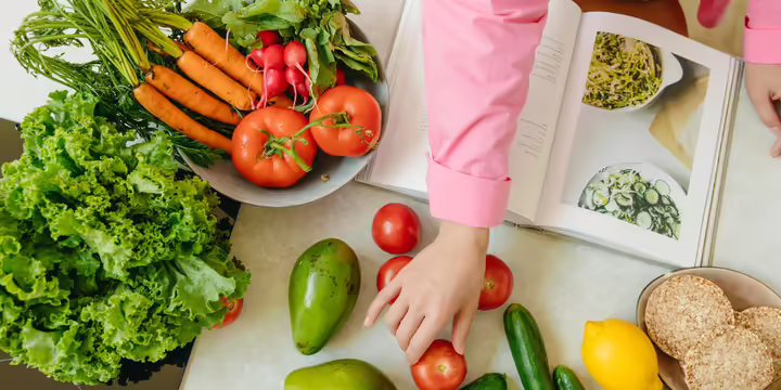 A display of fruits and vegetables, and a book on a table. 