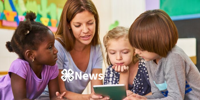 woman and three kids reading a newsletter on their ipad