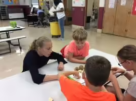 four children sitting around a table working on a recipe together