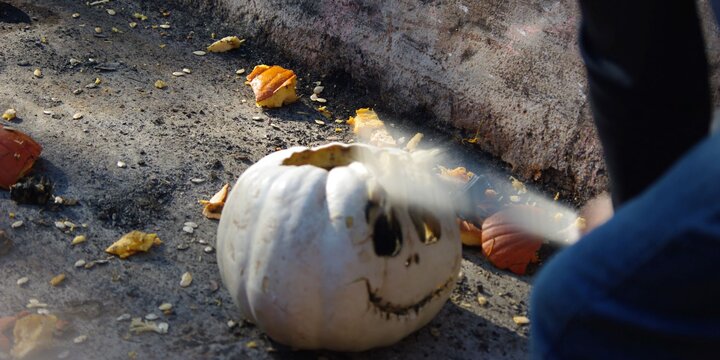 a white carved pumpkin is being smashed with a bat 