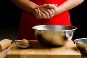 woman in red dress cracking an egg into a bowl