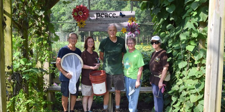 group of Master Gardeners standing under an arbor of pipevine