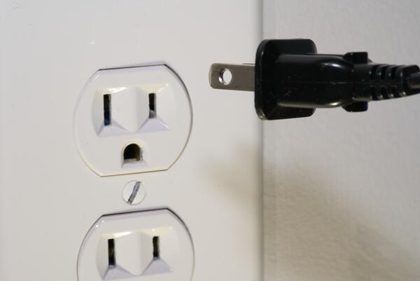 black plug going into white wall outlet