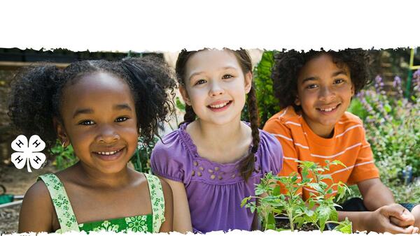 three younger kids holding vegetable plants and smiling