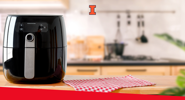 A black air fryer sitting on a counter top in a kitchen.