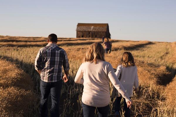 family walking thru field toward barn