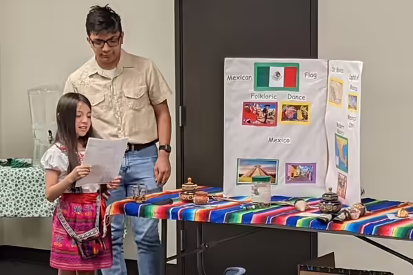 2 4-H members standing next to a table with a display about Mexico