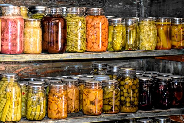 two rows of glass jars with vegetables