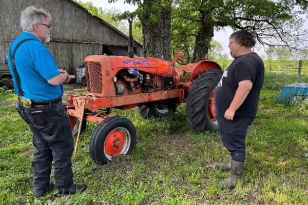 Farmer and AgrAbility client services rep assessing farm equipment.