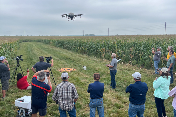 Crowd watching a drone seeding a field.