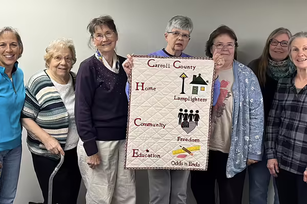 group of seven women with one holding a banner