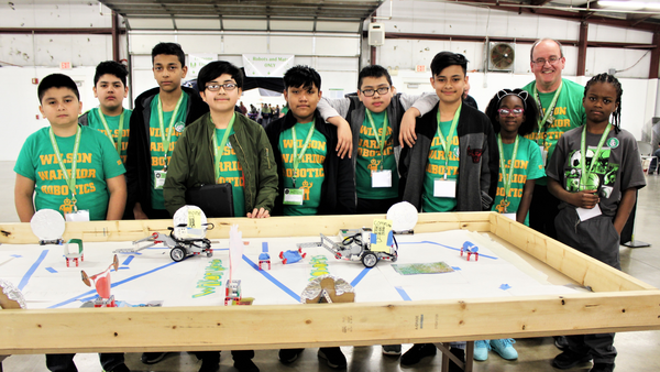 Youth pose around a robotics table.