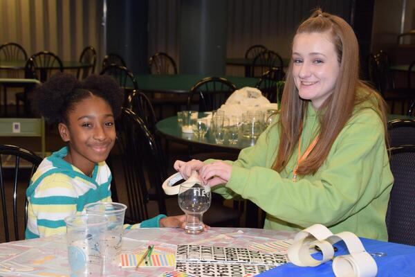 a teen ager helping a younger girl with a glass etching project