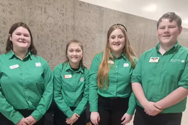 Members pose in green shirts in the Capitol.