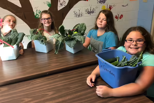 four girls sitting at a table with their basket of veggies