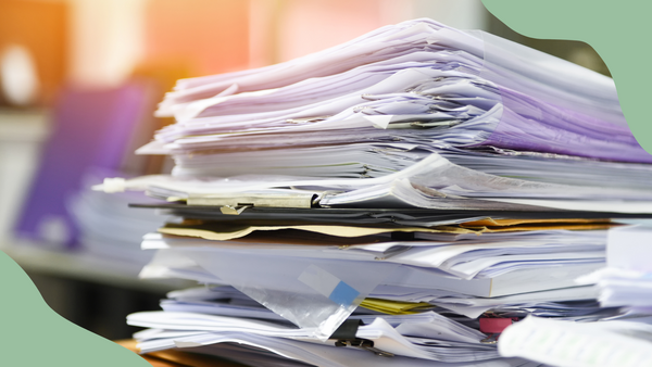 A stack of papers on a desk that are in a messy pile.