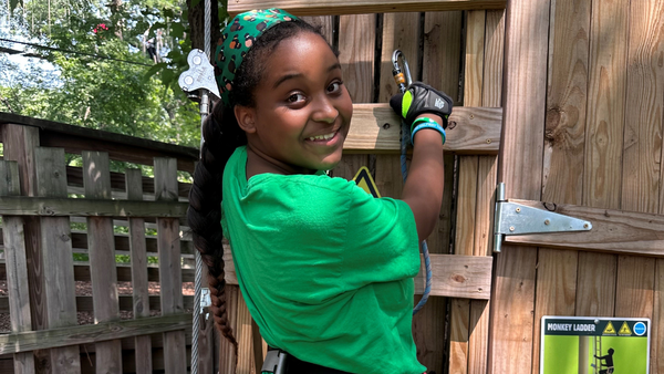 girl wearing green shirt posing for photo before climbing a ladder