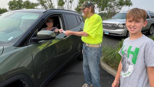 woman in drive-through fundraiser with man and boy volunteer