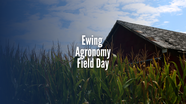 A barn next to a corn field with "Ewing Agronomy Field Day text.