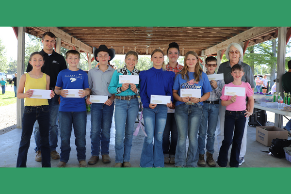 A group of 4-H youth hold up their checks from the farm bureau for winner the livestock shows.