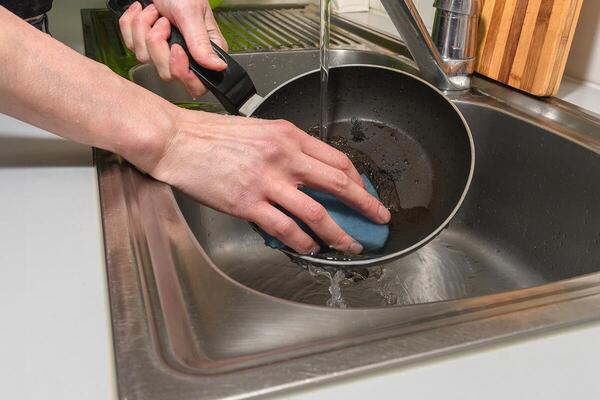 A hand scrubbing a non-stick pan