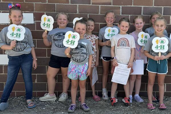 9 kids holding "I heart 4-H" fans