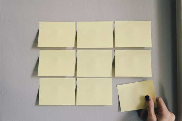 nine pieces of yellow sticky notes on a white wall