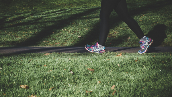 grass with legs in black leggings and tennis shoes walking