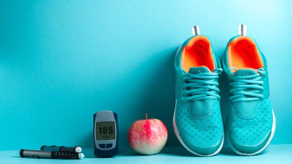 Shoes, an apple, and blood sugar reader in a line over a teal background.