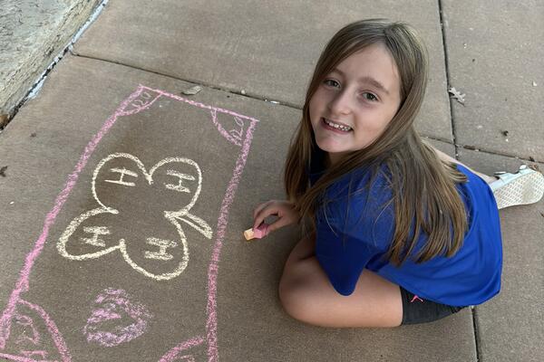 a 4-H member draws the 4-H logo with yellow chalk