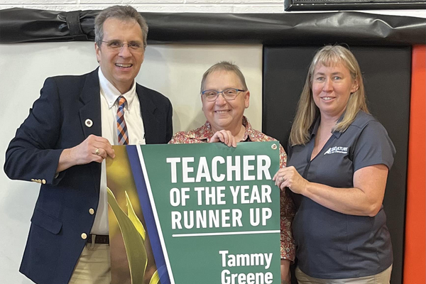 Three adults standing with sign that says teacher of the year runner-up