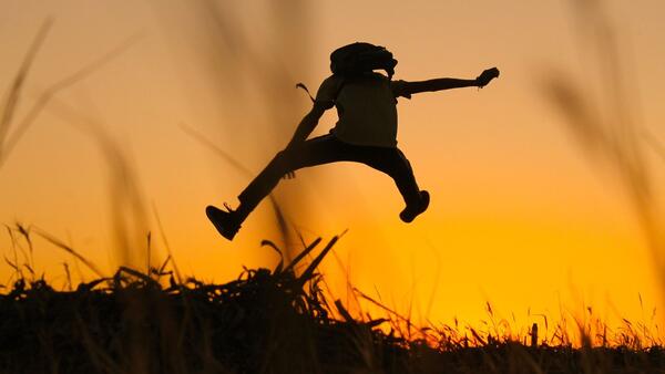 Silhouette of a person jumping up into the air.