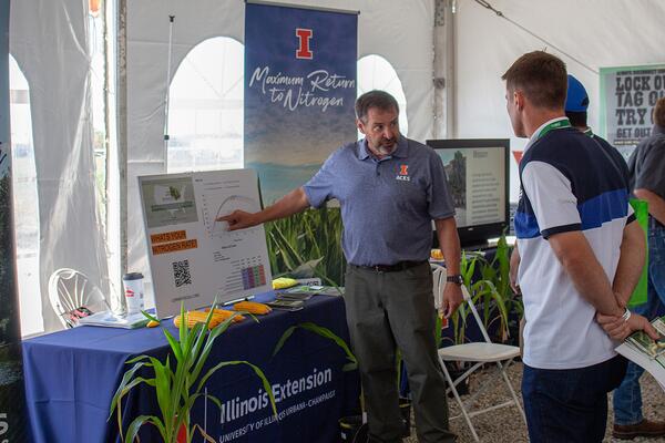 Extension staff member shares information about soil nitrogen with a person at at display booth