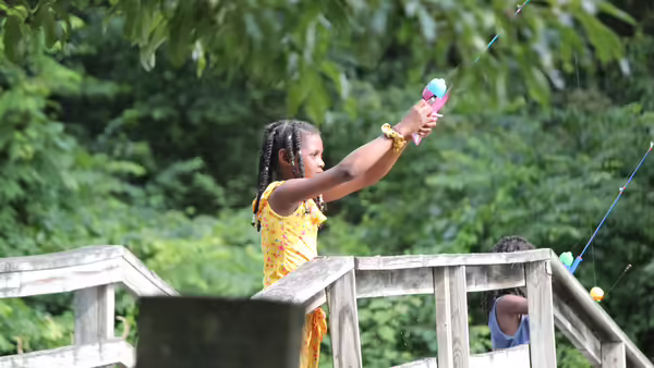 Girl fishes off a bridge.