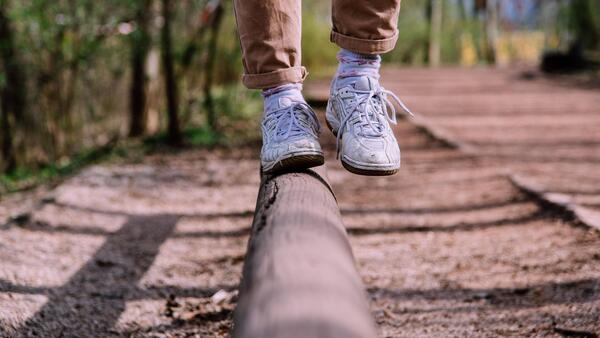 Close up of a person's feet in tennis shoes balancing on a log.