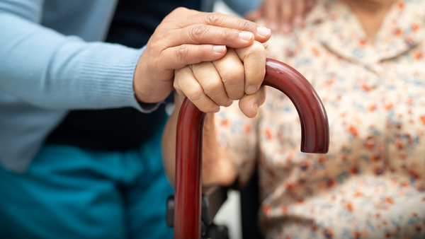 two hands resting on the top of a wooden walking care