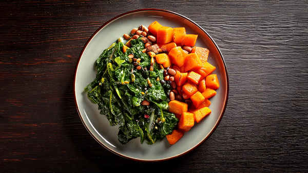 A plate of collard greens, sweet potatoes, and black eyed peas.