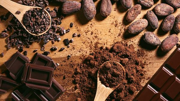 Chocolate bars and spoons with cocoa powder and cocoa heap 