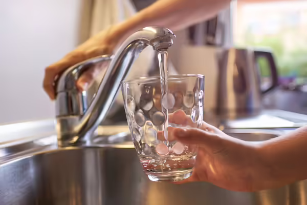 Someone filling a glass of water at the kitchen sink
