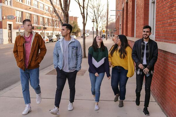 Five youth walking on sidewalk and laughing