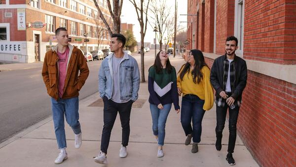 Five youth walking and laughing on a sidewalk