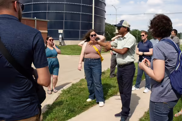 A man speaks to a group of people outside on a tour