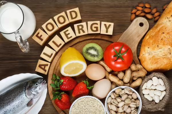 Variety of Food Allergy foods fish, nuts, milk, eggs, gluten, tomatoes, strawberries, on a table.