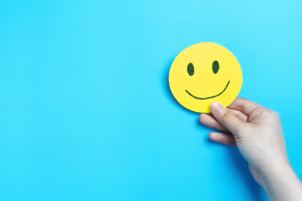 Person holding a drawing of a smiley face