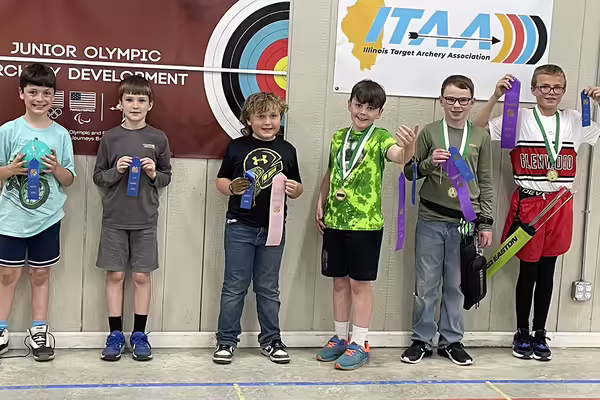six youth holding award ribbons and medals